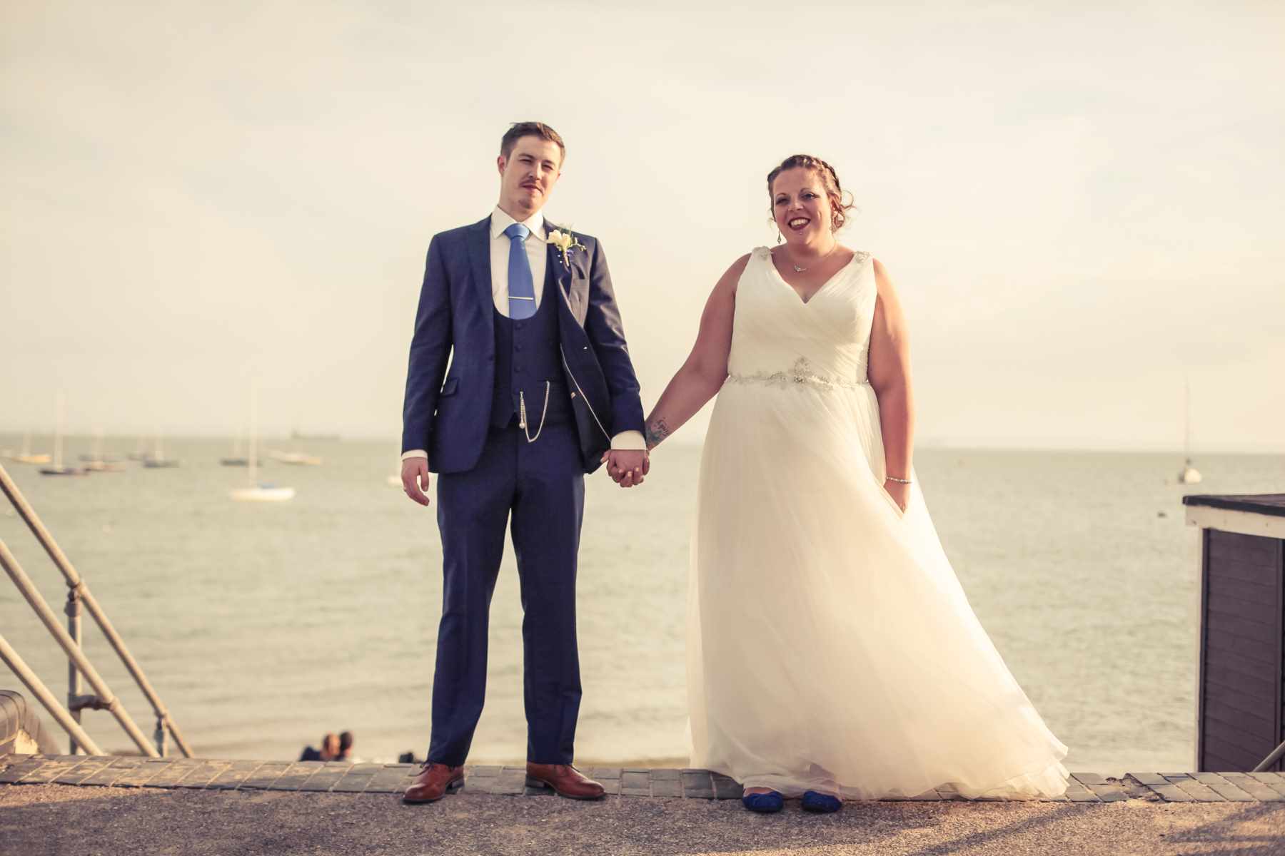 Bride and Groom holding hands at a wedding next to the sea in essex.