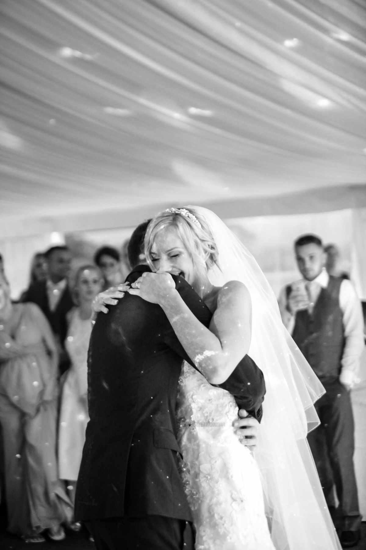 Bride holding onto her groom at her wedding whilst dancing. Romantic wedding photography.