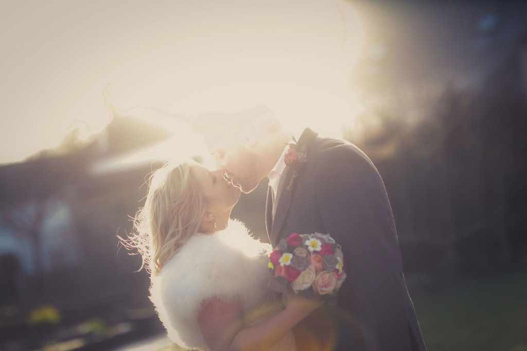 Kissing in the sun. Romantic wedding photo with vintage colours.