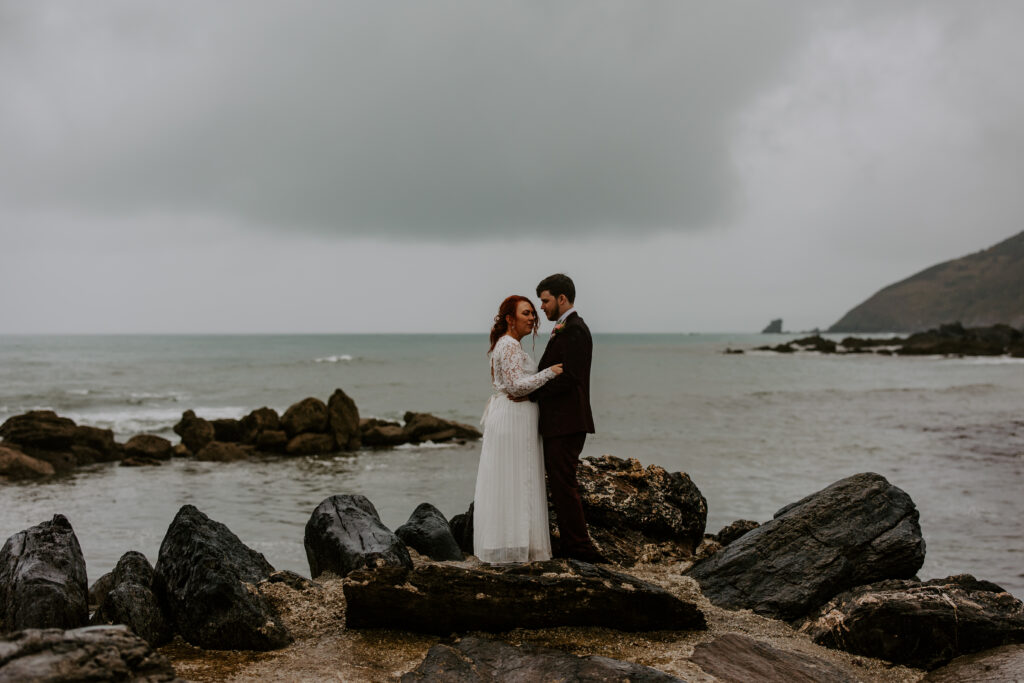 standing on a rock at Cornish beach wedding