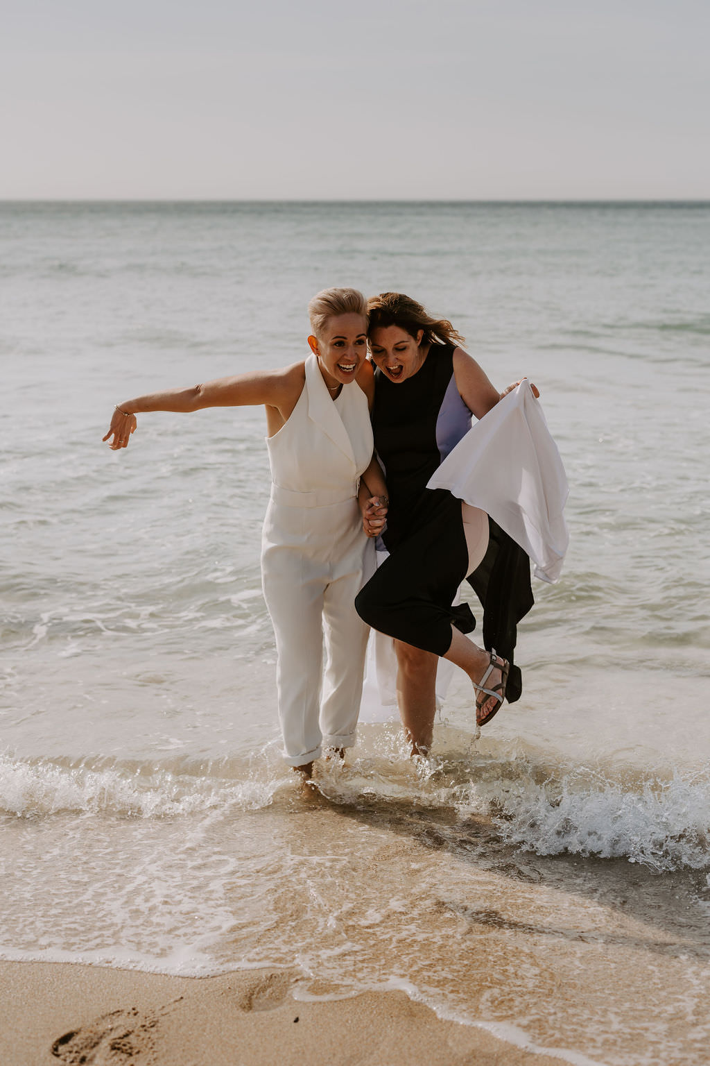 A wedding couple splashing through the Cornish sea